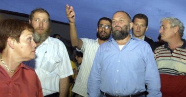 In this Oct. 13, 2002 file photo, Israel's then-Infrastructure Minister Effie Eitam (C) listens to Jewish settlers when visiting Mitzpeh Assaf, an illegal outpost which Israel's Defense Minister said will be dismantled, near the settlement of Ofra, north of Jerusalem. (AP Photo)