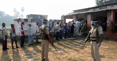 Policemen wearing protective face shields stand guard as voters stand in a queue to cast their vote outside a polling booth at a village on the outskirts of Patna in the eastern state of Bihar, India, Oct. 28, 2020. (REUTERS Photo)
