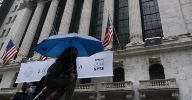 A woman with an umbrella passes the New York Stock Exchange, Monday, Oct. 26, 2020 (AP Photo)