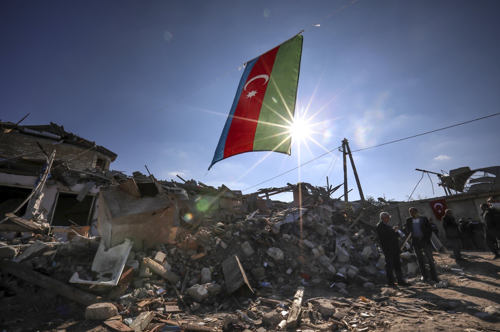 Azerbaijan's national flag flies over destroyed houses in a residential area that was hit by rocket fire overnight by Armenian forces, on Thursday, Oct. 22, 2020 in Ganja, Azerbaijan's second largest city, near the border with Armenia. (AP Photo)