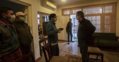 Agence France-Presse’s Kashmir correspondent Parvaiz Bukhari (C), talks to his colleagues after National Investigation Agency personnel searched his premises on the outskirts of Srinagar, Indian controlled Kashmir, Oct. 28, 2020. (AP Photo)