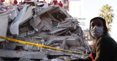 A local resident watches as rescue teams search for survivors in the debris of a collapsed building in Izmir, Turkey, Oct. 31, 2020. (AP Photo)