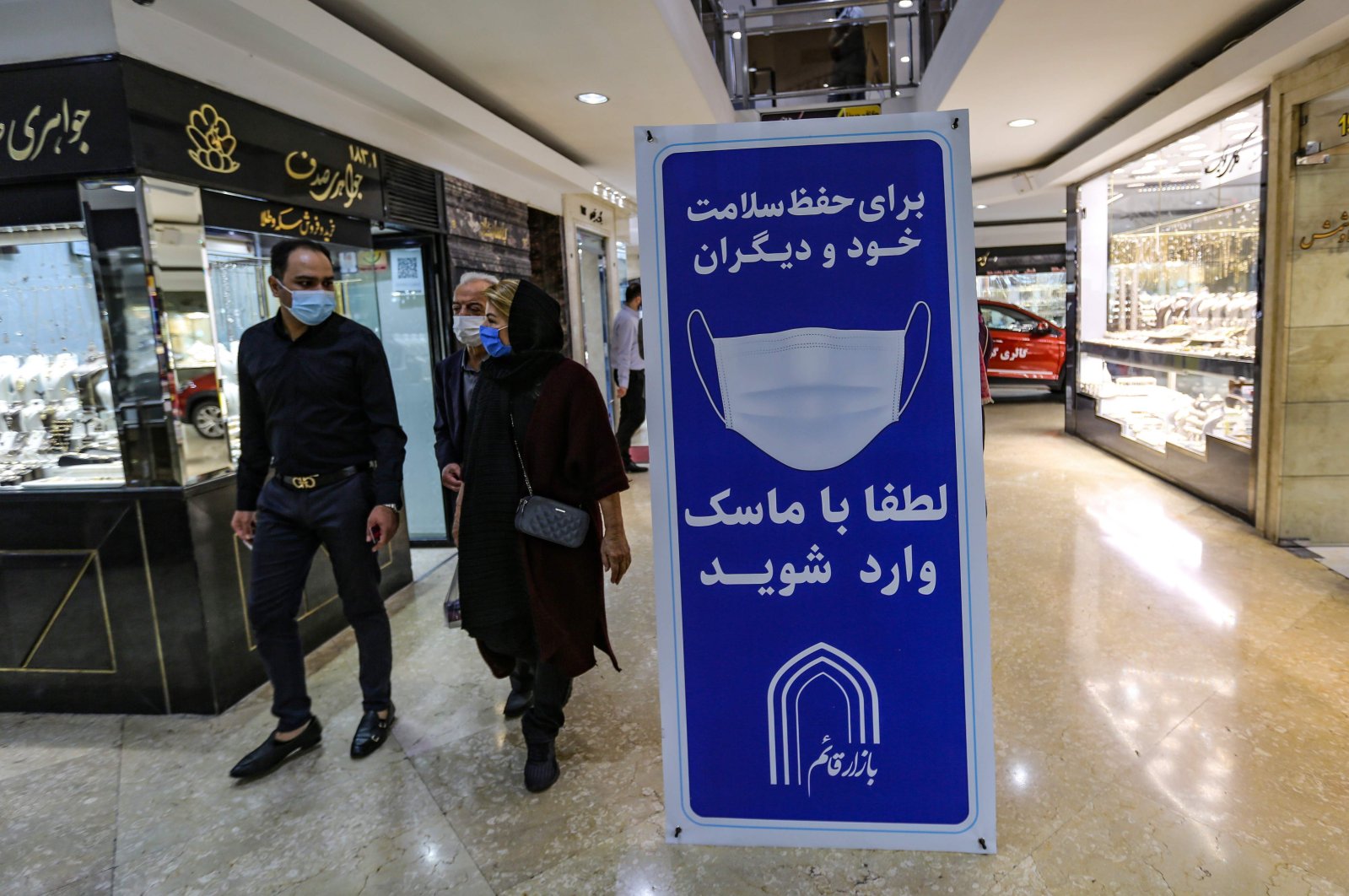 Iranians walk next to a sign advising people to wear masks on their way to shop in Tajrish square in the capital Tehran on Nov. 1, 2020, amid the COVID-19 pandemic crisis. (AFP Photo)