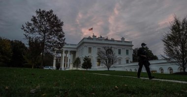 A U.S. agent walks down a path as the sun rises over the White House in Washington, D.C., Nov. 1, 2020. (AFP Photo)