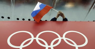 A Russian skating fan holds the country's national flag over the Olympic rings before the men's 10,000-meter speedskating race during the Winter Olympics in Sochi, Russia, Feb. 18, 2014. (AP Photo)