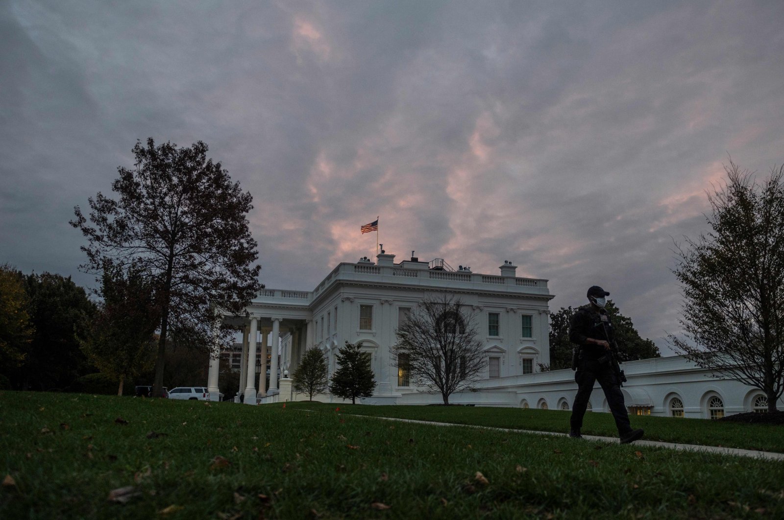 A U.S. agent walks down a path as the sun rises over the White House in Washington, D.C., Nov. 1, 2020. (AFP Photo)