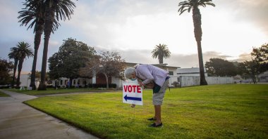 Lorraine Crawford puts vote signs as the sin rises the Main Street Branch Library vote center on November 3, 2020 in Huntington Beach, California. (AFP Photo)