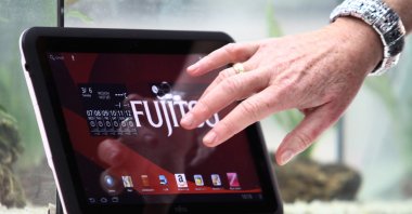 A woman touches a water resistant Fujitsu tablet PC at the information technology fair CEBIT in Hanover, Germany, March 6, 2012.  (EPA Photo)