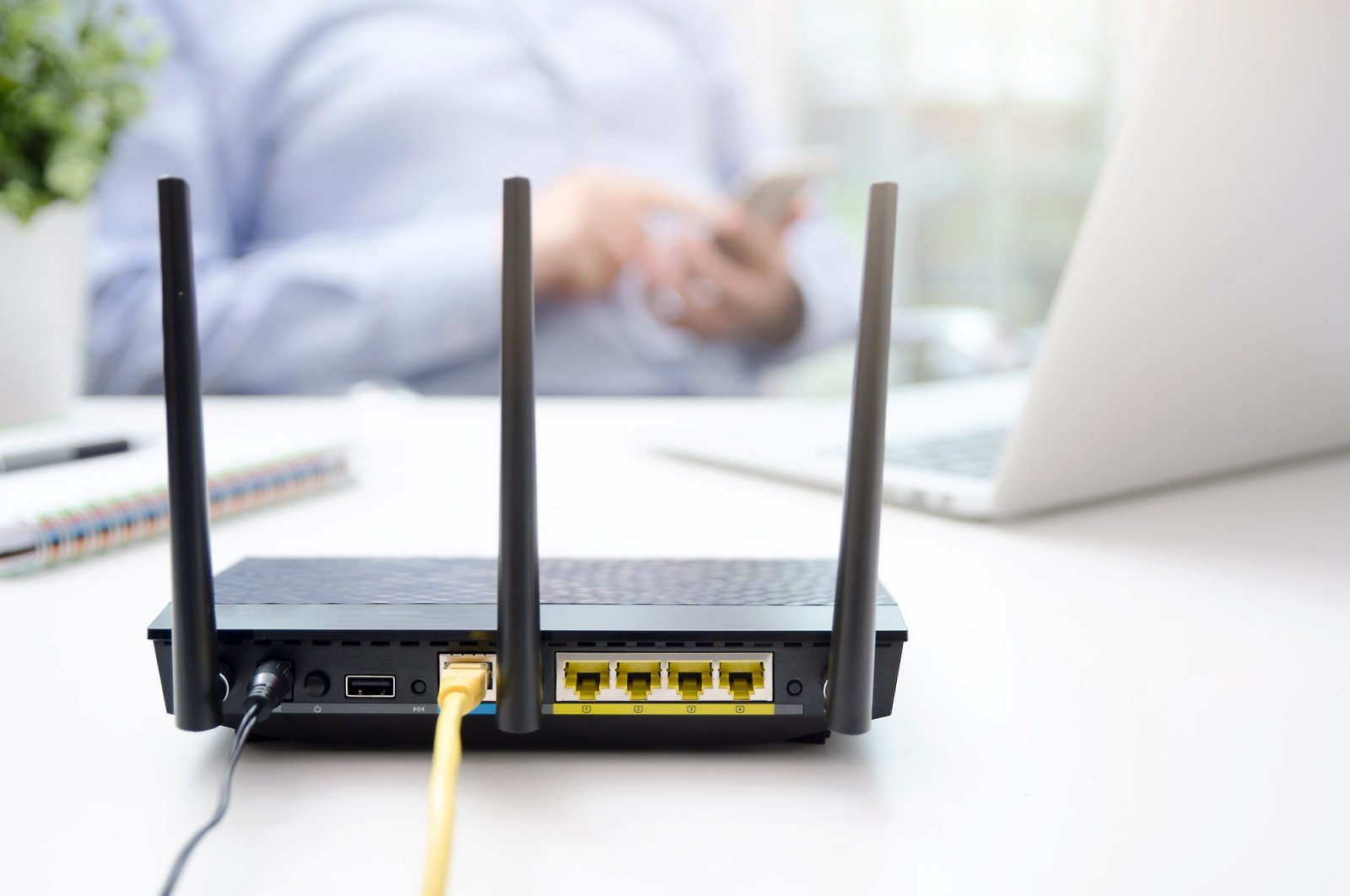 A wireless router seen as a man a smart phone. (Shutterstock Photo)