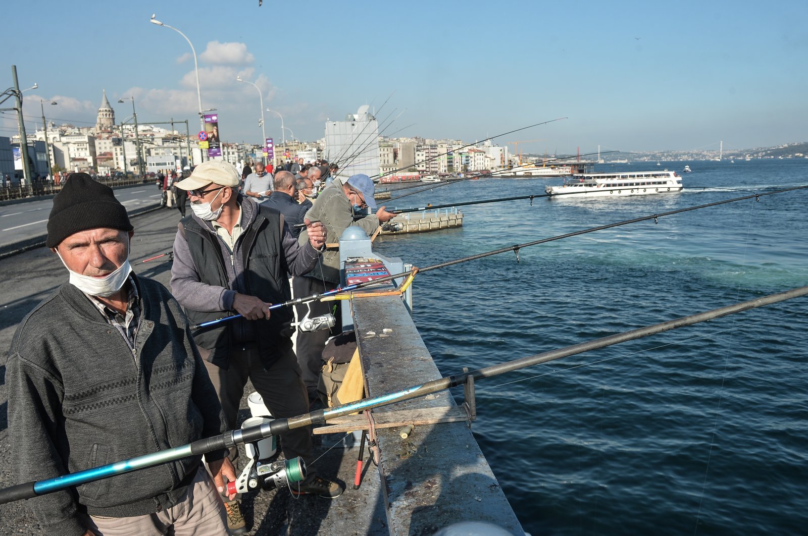 Fishermen cast their lines off Galata Bridge, some wearing masks to protect against COVID-19, in Istanbul, Turkey, Nov. 2, 2020. (DHA Photo)