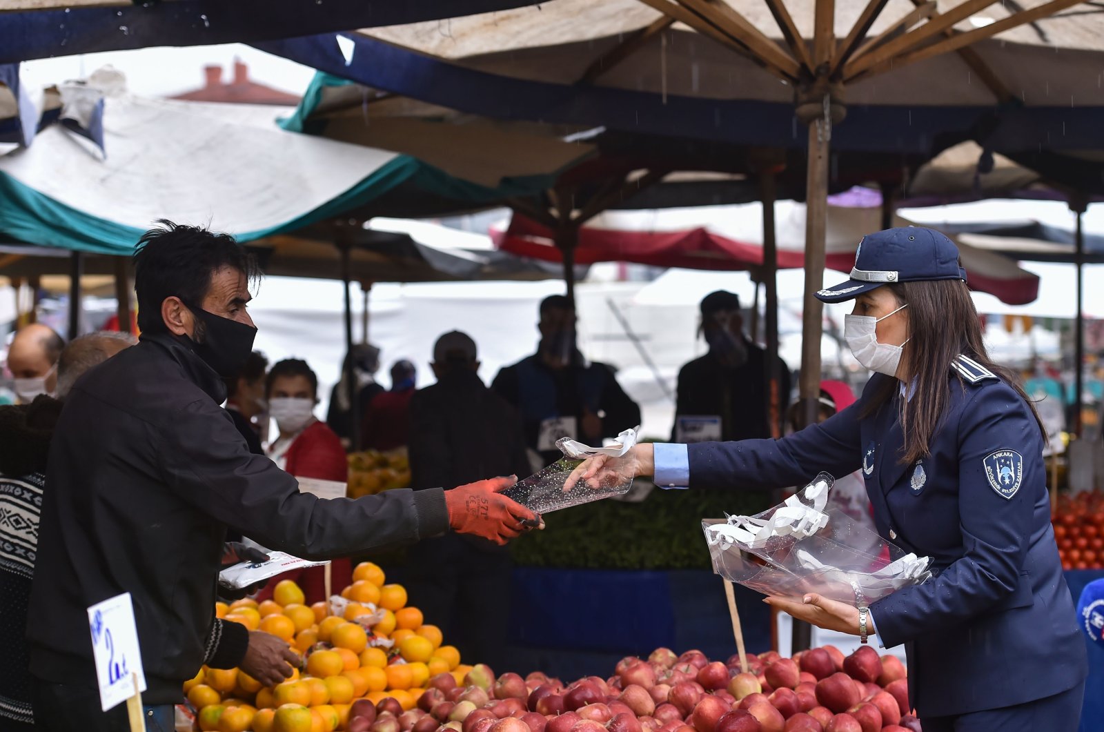 An Ankara municipal police officer hands a face shield to a fruit vendor at a market in the capital Ankara, Turkey, Nov. 3, 2020. (IHA Photo)