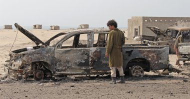 A Yemeni southern separatist fighter inspects the wreckage of government forces vehicles destroyed by UAE airstrikes near Aden, Yemen, Aug. 30, 2019. (AP Photo)