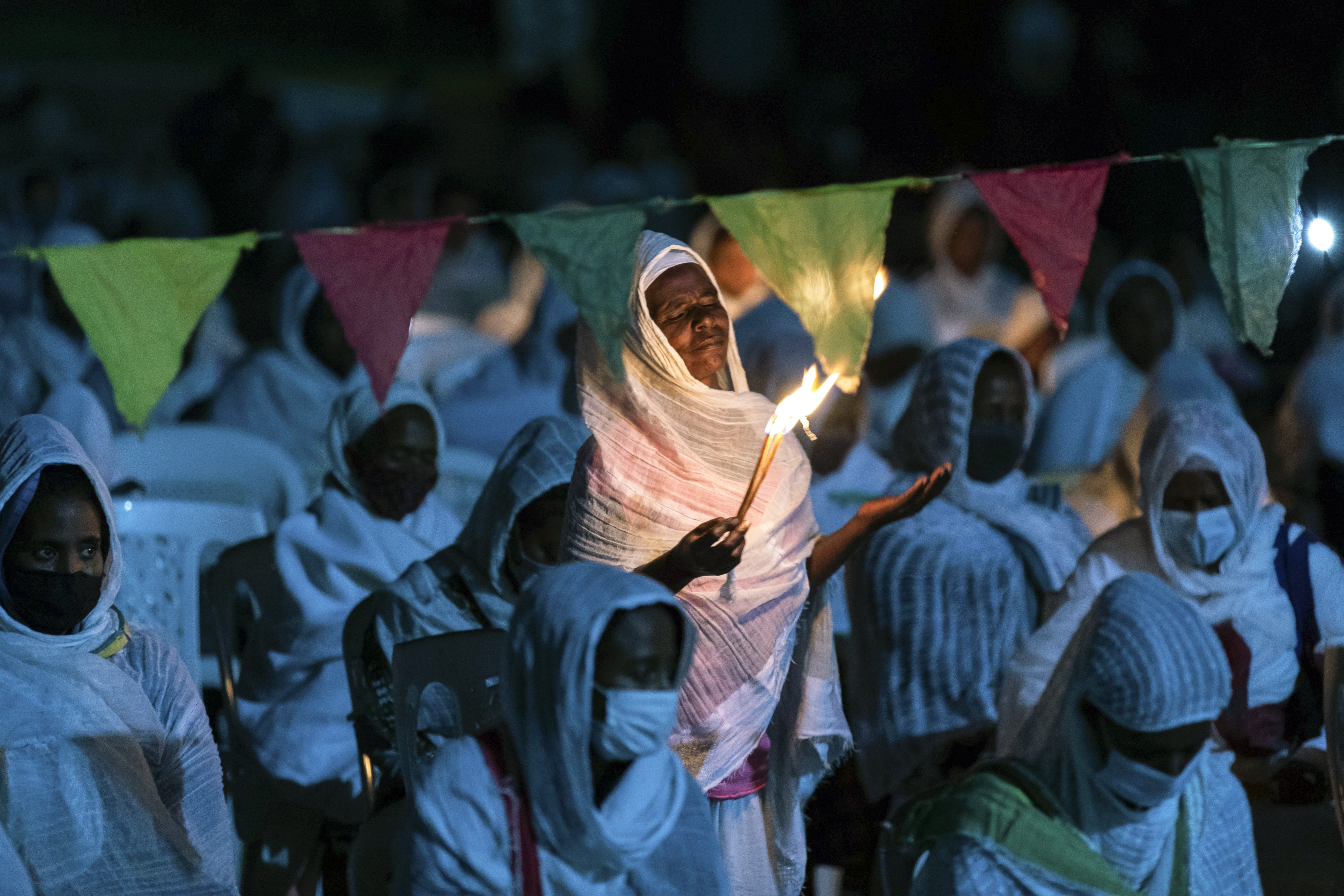 Ethiopian Orthodox Christians light candles and pray for peace during a church service at the Medhane Alem Cathedral in the Bole Medhanealem area of the capital. Ethiopia's powerful Tigray region asserts that fighter jets have bombed locations around its capital, Mekele, aiming to force the region "into submission," while Ethiopia's army says it has been forced into an "unexpected and aimless war," Addis Ababa, Ethiopia, Nov. 5, 2020 (AP Photo/Mulugeta Ayene)