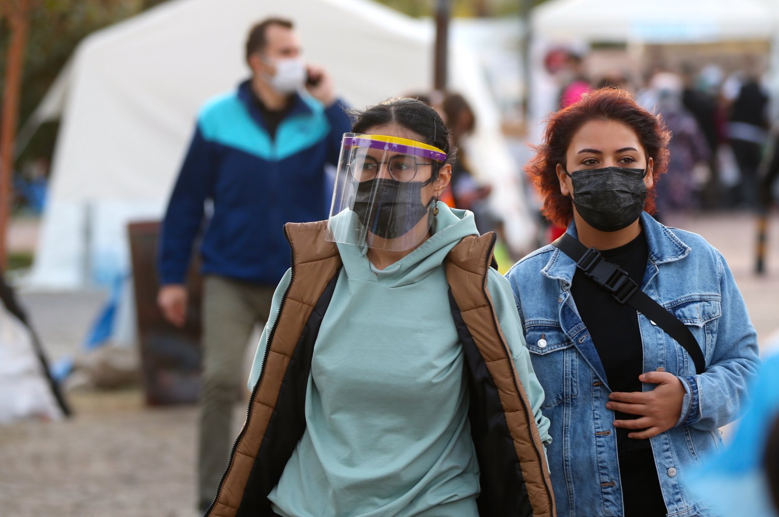 Two young women donning face masks and shields walk at a tent city in the western city of Izmir, which was hit by an earthquake on Oct. 30, 2020 killing 114 people and injured hundreds more, leaving thousands homeless or in search of more secure buildings, on Nov. 7, 2020. (AA Photo)