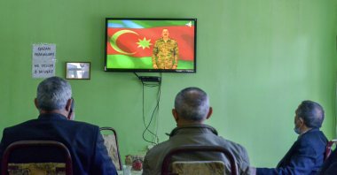 People listen to Azerbaijan's President Ilham Aliyev speaking on a television at a teahouse in Barda, Azerbaijan, Nov. 8, 2020. (AP Photo)