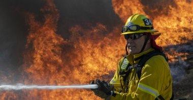 A firefighter protects a home from getting too hot as a backfire is set to protect homes and try to contain the Blue Ridge Fire on October 27, 2020 in Chino Hills, California. (AFP Photo)