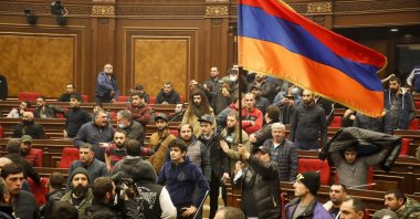 Demonstrators wave an Armenian flag in protest against a peace deal over the Nagorno-Karabakh region, at the national parliament building in Yerevan, Armenia, Tuesday, Nov. 10, 2020. (AP Photo)