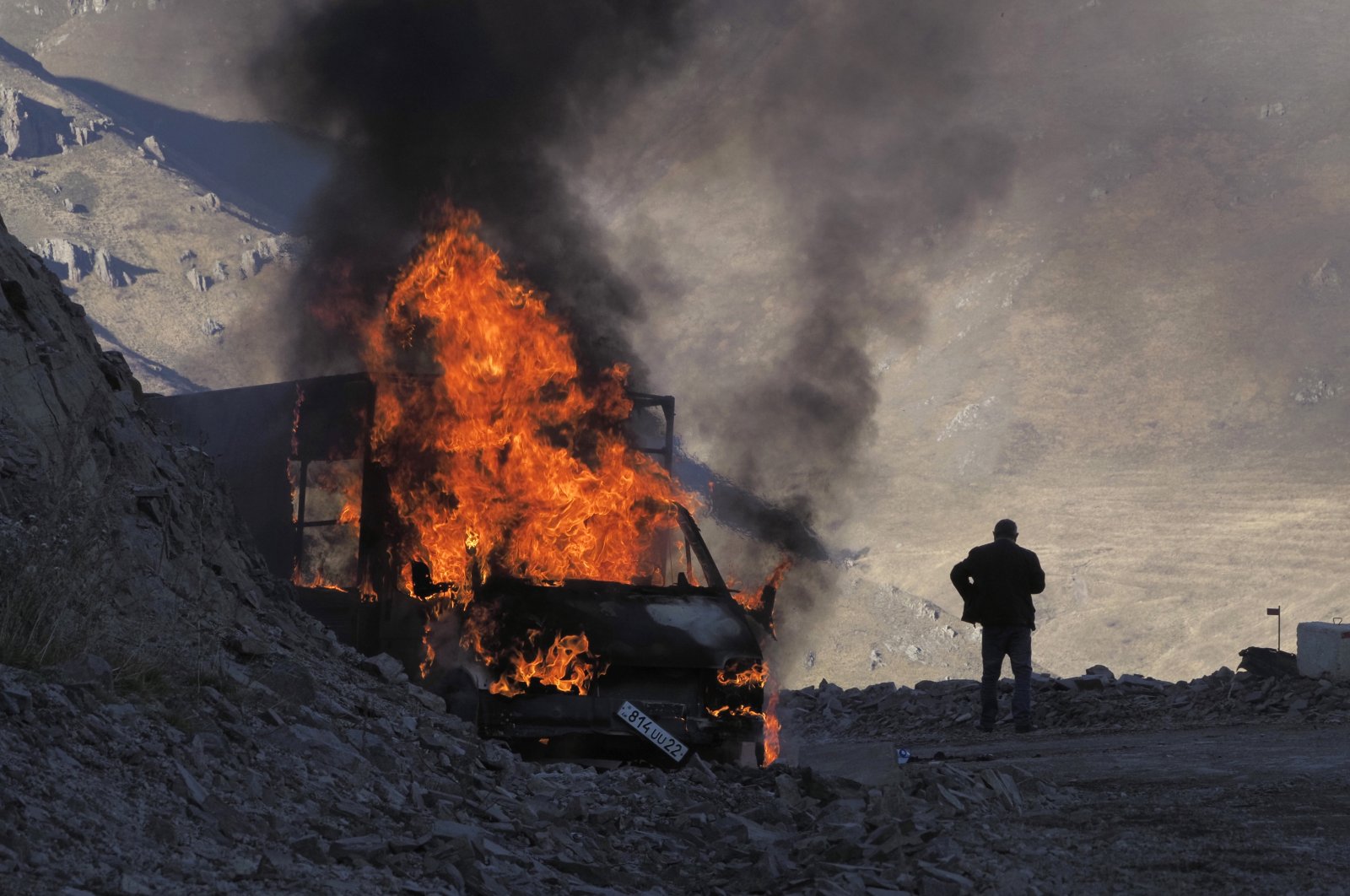 A man stands near his burning car which caught on fire during the climb along the road to a mountain pass, near the border between Nagorno-Karabakh and Armenia, Sunday, Nov. 8, 2020. (AP Photo)