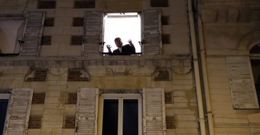 French tenor singer Stephane Senechal sings at dusk, the U.S. national anthem and Tosca of Puccini, from his apartment window during the monthlong partial lockdown to stop fast-rising virus hospitalizations and deaths, in Paris, Monday, Nov. 09, 2020. (AP Photo)