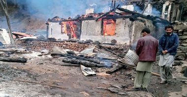 Local residents stand beside a burning house following cross-border shelling between Pakistani and Indian forces in the village of Tehjain at the Line of Control (LoC), the de facto border between Pakistan and India, in Neelum Valley of Pakistan-administered Kashmir, Nov. 13, 2020. (AFP Photo)