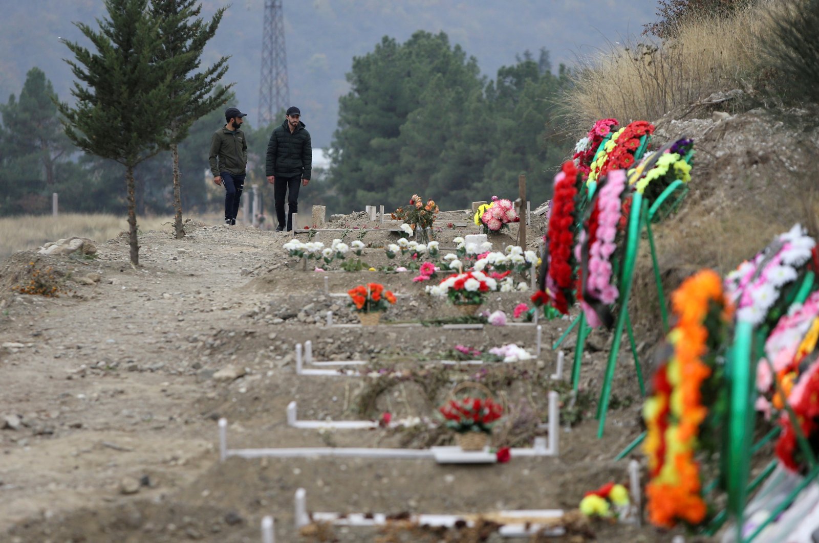 Men walk along graves of soldiers and civilians who were killed during clashes over Nagorno-Karabakh, in Stepanakert, Nov. 2, 2020. (Reuters Photo)