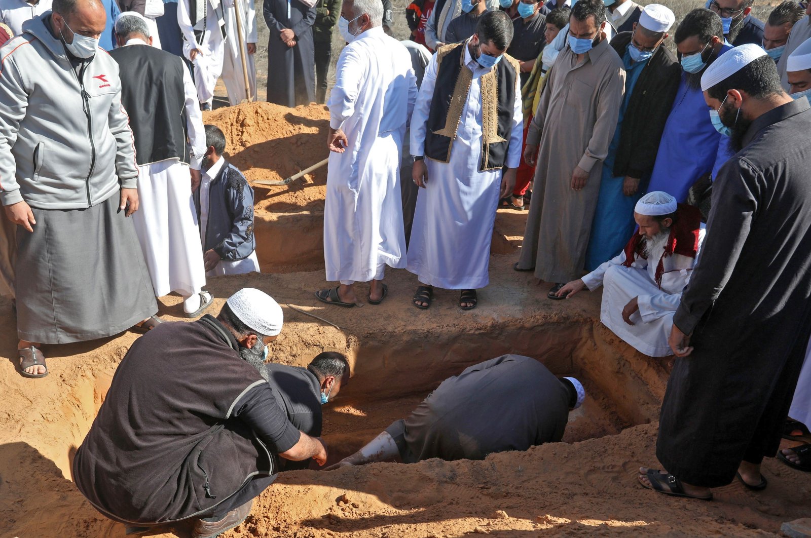 Libyan mourners bury a body, that has been unearthed from a mass grave, in a cemetery in the city of Tarhuna on Nov. 13, 2020. (AFP Photo)