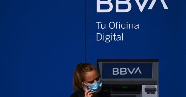 A woman uses a smartphone in front of an ATM of the BBVA in Madrid, Spain, Sept. 4, 2020. (AFP Photo)