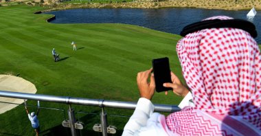 A Saudi man watches a golfer compete in the Saudi Ladies International golf tournament at the King Abdullah Economic City, north of Jeddah, (AFP Photo)