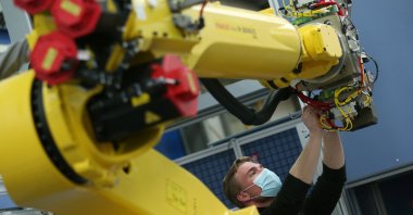 An employee works on an industrial robot at HAHN Automation company in Rheinboellen, Germany, Nov. 11, 2020.  (Reuters Photo)