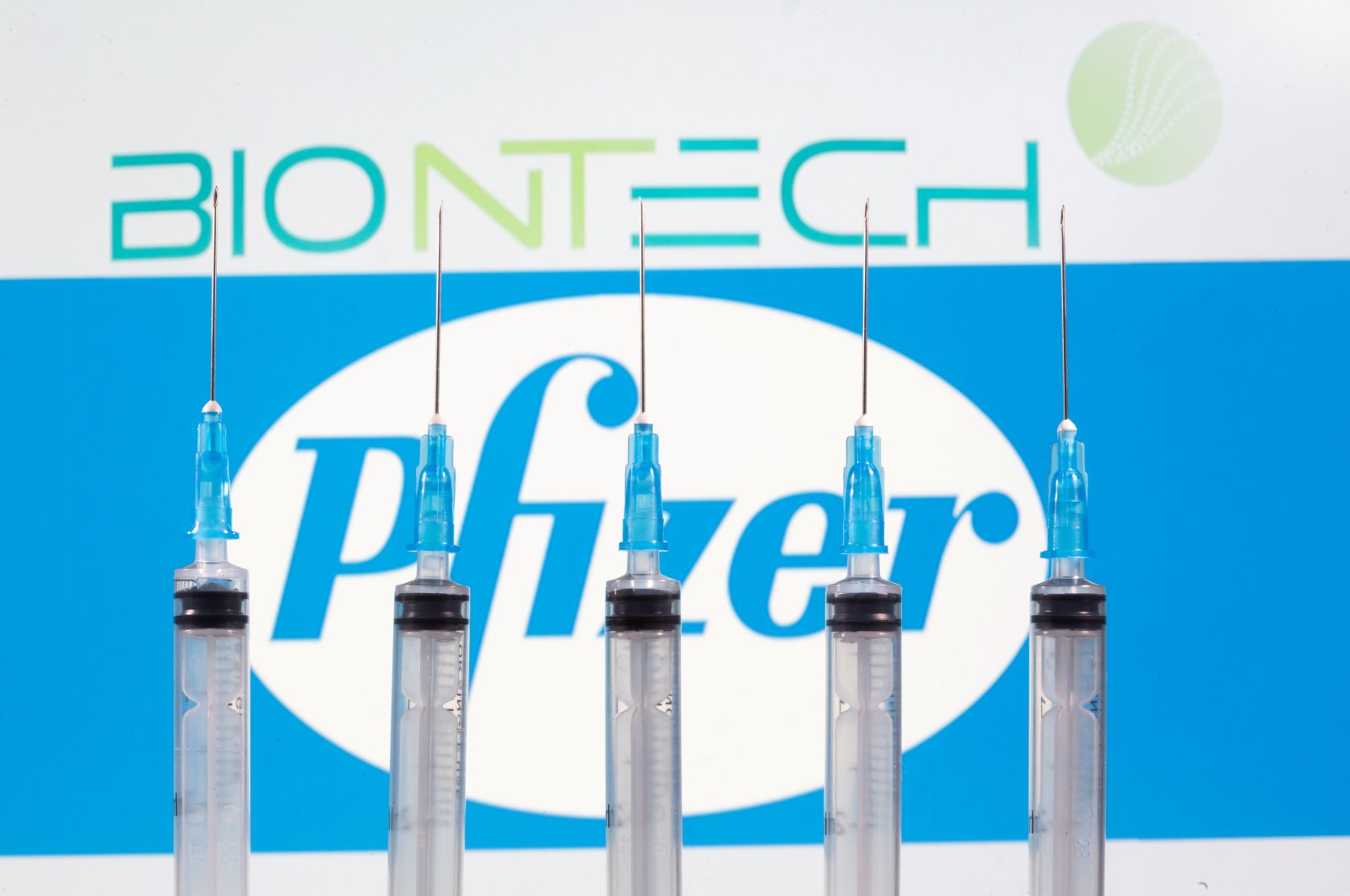 Syringes seen in front of displayed BioNTech and Pfizer logos in this illustration. (REUTERS/File Photo)