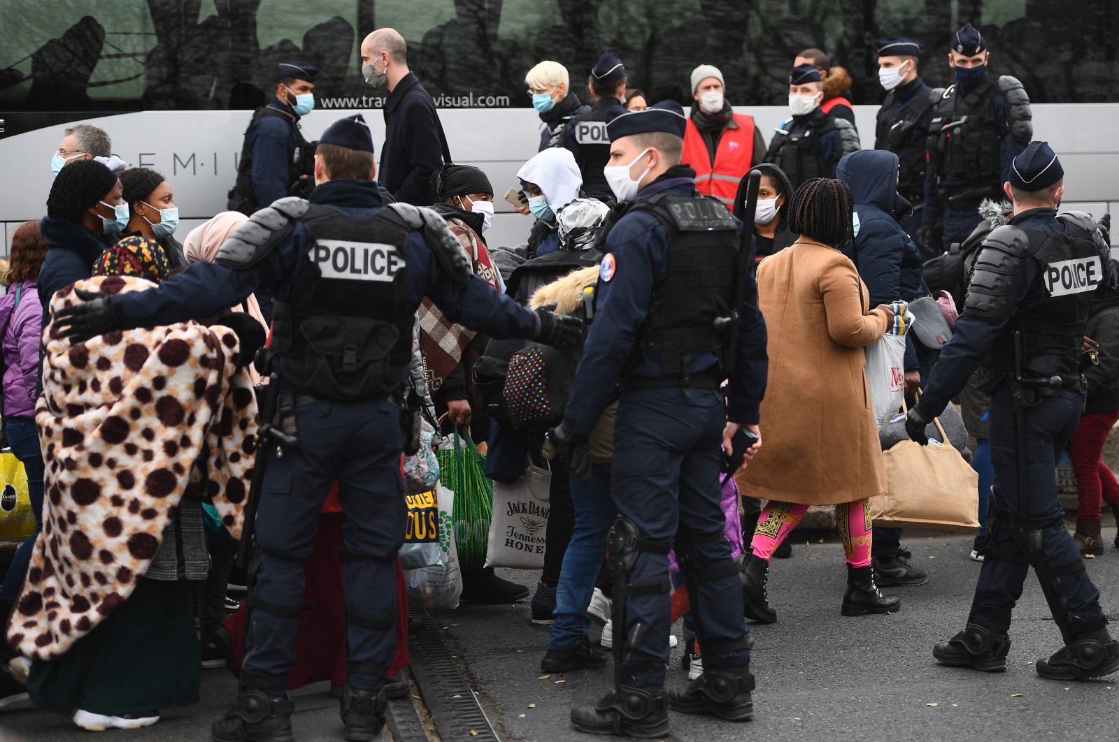 Migrants wait to be taken to shelters after French police raided a makeshift camp set up below the A1 highway in the north of Paris' popular suburb of Saint-Denis, France, Nov. 17, 2020. (AFP Photo)