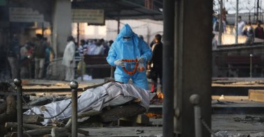 A relative places a garland on the body of a COVID-19 victim during the cremation in New Delhi, India, Nov. 19, 2020. (AP Photo)