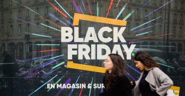 Pedestrians walk past a store window with a sign announcing "Black Friday" sales, Paris, France, Nov. 23, 2018. (AFP Photo)