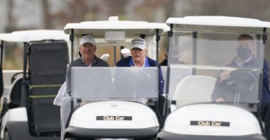 U.S. President Donald Trump, center, drives a golf cart as he golfs at Trump National Golf Club in Sterling, Va., Nov. 22, 2020. (AP Photo)