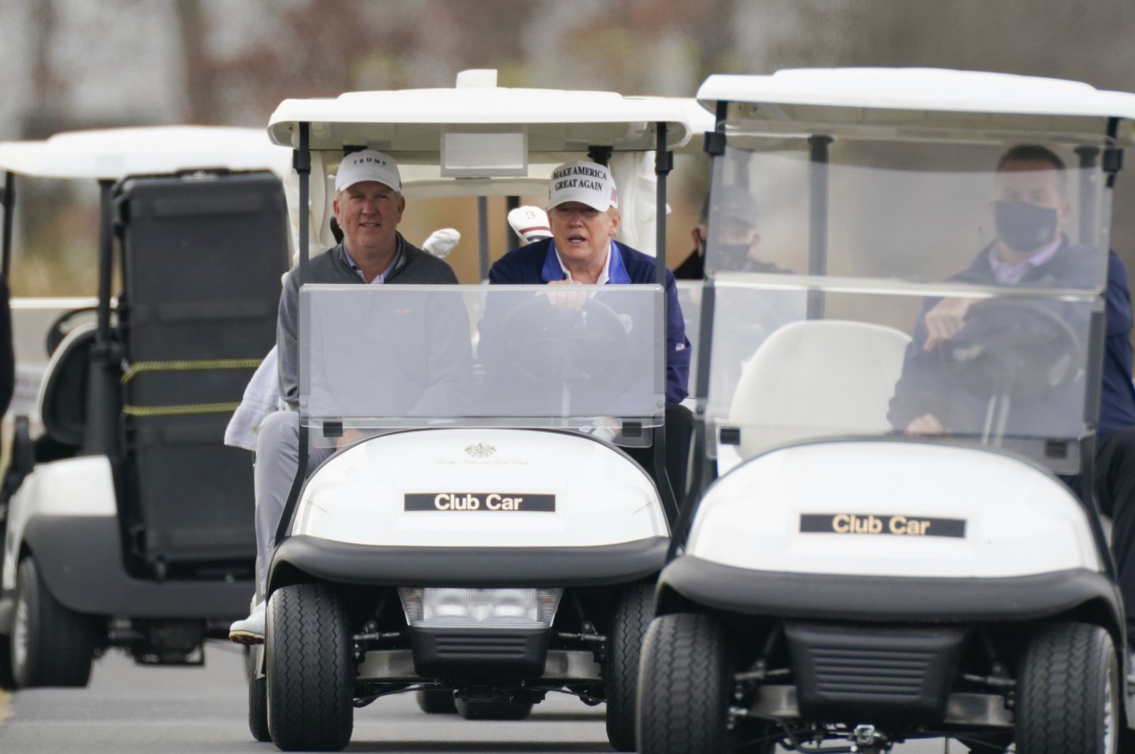 U.S. President Donald Trump, center, drives a golf cart as he golfs at Trump National Golf Club in Sterling, Va., Nov. 22, 2020. (AP Photo)