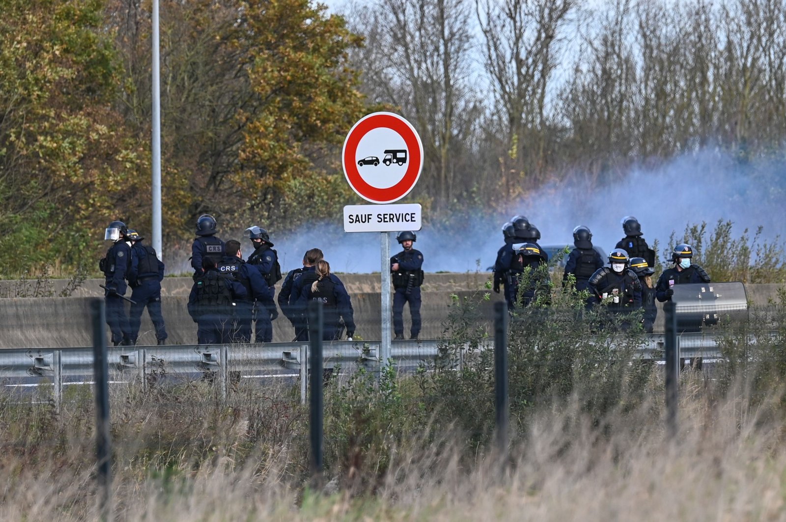 Police push back away from the A16 motorway migrants attempting to climb into the back of lorries bound for Britain, in Calais, northern France, Nov. 19, 2020. (AFP Photo)
