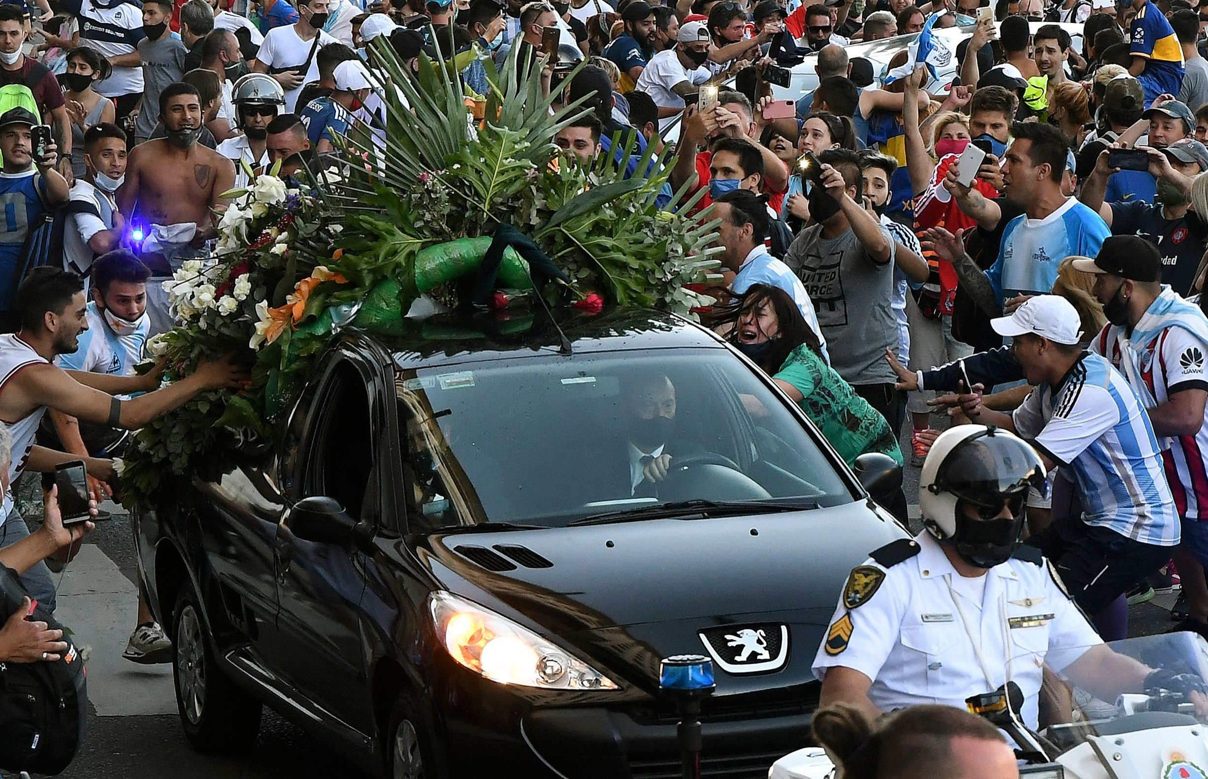 Photo released by Telam showing fans crowding next to the hearse carrying the late Argentine football legend Diego Armando Maradona while leaving Casa Rosada presidential palace to the cemetery, in Buenos Aires, Nov. 26, 2020. (Telam via AFP)