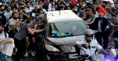 Photo released by Telam showing fans crowding next to the hearse carrying the late Argentine football legend Diego Armando Maradona while leaving Casa Rosada presidential palace to the cemetery, in Buenos Aires, Nov. 26, 2020. (Telam via AFP)
