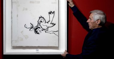 An employee of the auction house Hessink presents the graffiti painting "Bird with Grenade," made by artist Banksy, in Zwolle, the Netherlands,  Nov. 26, 2020. (AFP PHOTO)