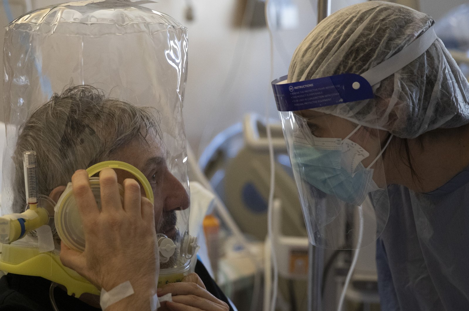 A patient breathing under oxygen CPAP (continuous positive air pressure) headgear ventilation talks to a doctor in the sub-intensive COVID-19 unit of the Tor Vergata Polyclinic Hospital, in Rome, Nov. 7, 2020. (AP Photo)