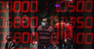 People wearing protective masks against the spread of the coronavirus are seen reflected at a foreign currency exchange shop at the iconic 15th century Grand Bazaar in Istanbul, June 1, 2020. (AP Photo)