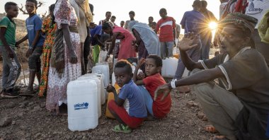Tigray women and men who fled the conflict in Ethiopia's Tigray region, wait in line to pour water into gallons, at Umm Rakouba refugee camp in Qadarif, eastern Sudan, Friday, Nov. 27, 2020. (AP Photo)