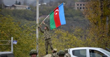 An Azerbaijani soldier fixes a national flag on a lamppost in the town of Lachin, southwestern Azerbaijan, Dec. 1, 2020. (AFP Photo)