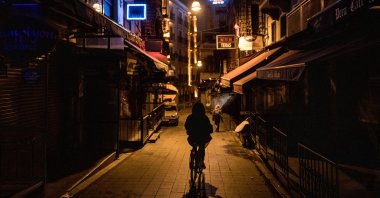 A man rides a bike down a near-empty restaurant street as a new weekday curfew comes into effect in Istanbul, Dec. 1, 2020.  (Photo by Getty Images)