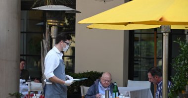 A server wearing a mask and face shield takes orders from customers at a restaurant in Beverly Hills, California, U.S., Nov. 23, 2020. (AFP Photo)