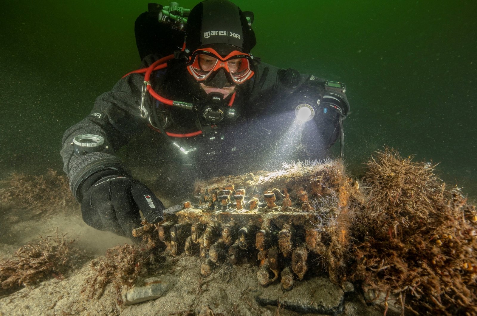 Diver and underwater archaeologist Florian Huber touches a rare Enigma cipher machine used by the Nazi military during World War II, in Gelting Bay near Flensburg, Germany on Nov. 11, 2020. (Reuters Photo)