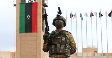 A Libyan soldier poses in front of the Libyan flag during a graduation ceremony concerning a military training program between Ankara and Tripoli, where the joint land training center Omar Mukhtar is located, on Nov. 21, 2020. (AA Photo)