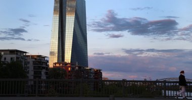 A woman, wearing a protective mask walks past the headquarter of the European Central Bank (ECB) during sunset in Frankfurt, Germany, April 29, 2020. (Reuters Photo)