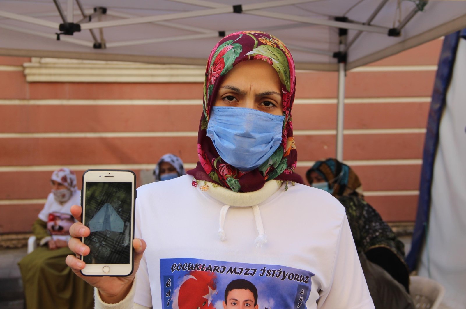 Ayşegül Biçer shows the picture of the death threat sent to her home by PKK terrorists on her phone while wearing a T-shirt with a picture of her abducted child, Mustafa, Diyarbakır, Turkey, Nov. 17, 2020. (DHA)