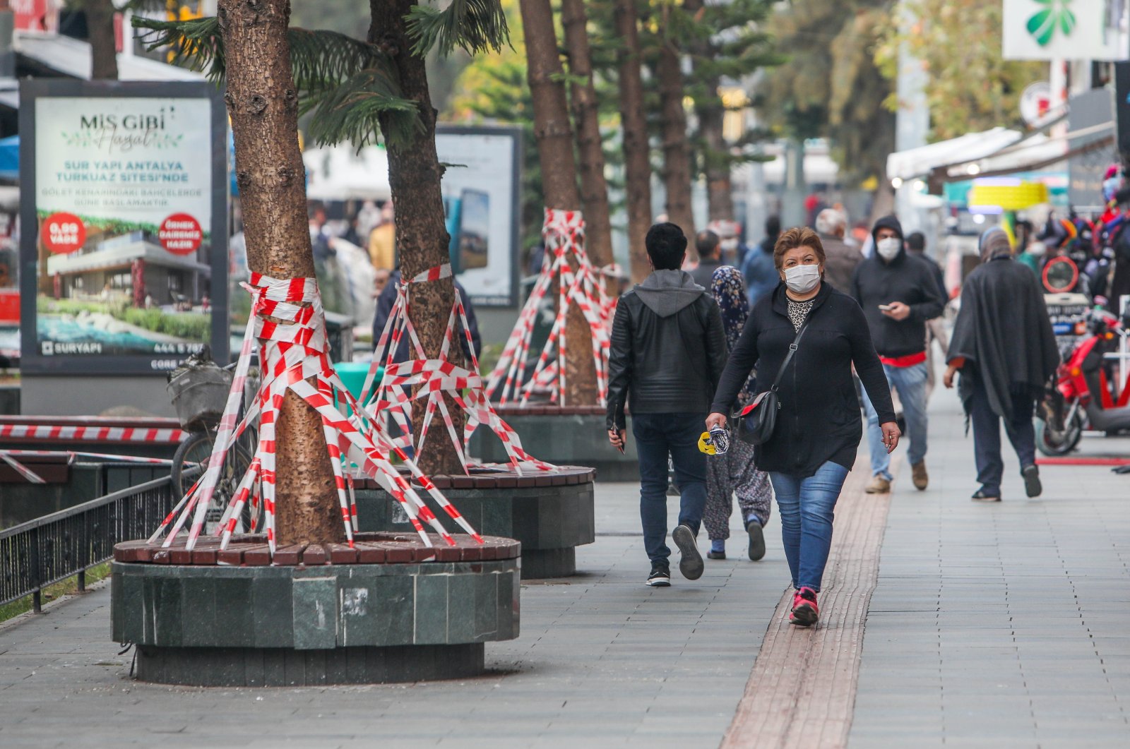 People wearing protective masks walk next to benches covered with tape to prevent crowding, in Antalya, southern Turkey, Dec. 7, 2020. (DHA Photo)